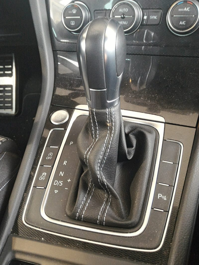 Alavanca de câmbio automático de um Golf da sétima geração, com coifa de couro de costura dupla clara e as posições P, R, N e D/S marcadas no console, além dos sinais + e – para trocas manuais
