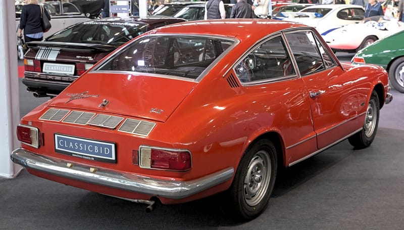 Traseira de um Karmann-Ghia TC vermelho, com a tampa traseira grande e inclinada, grelhas de ventilação do motor no painel traseiro e lanternas retangulares