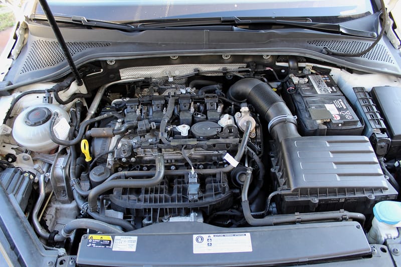 Cofre de um Volkswagen branco com o motor 2.0 TSI montado na transversal: quatro bobinas de ignição em linha sobre a tampa de válvulas, coletor de admissão plástico preto na frente, vareta de óleo amarela à esquerda e caixa do filtro de ar à direita